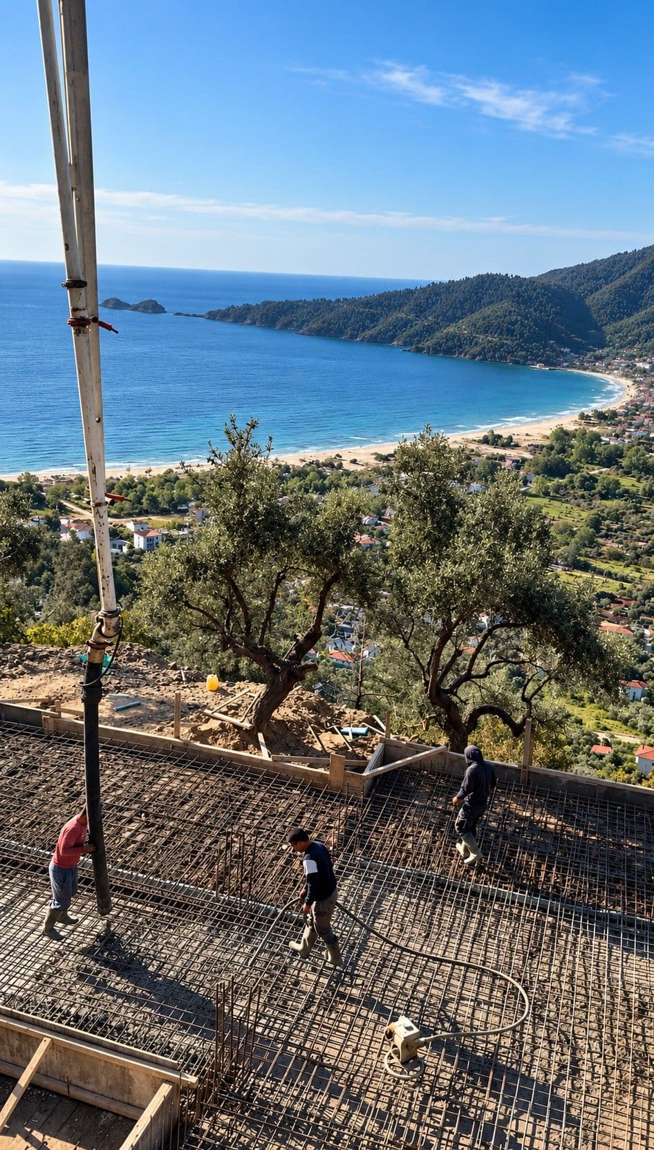 The construction site above the bay: workers on the steel reinforcement of the foundation slab while concrete is poured through a pump hose, with olive trees, the beach and the sea behind.
