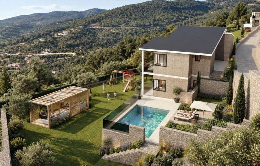 Villa 1 from above in daylight: pool with a glass edge, lawn, play area and pergola, with wooded hills behind.